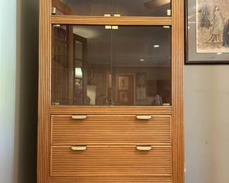 Rounded rattan display cabinet with glass front storage brass tone trim and lower drawers from the Tom Culver estate