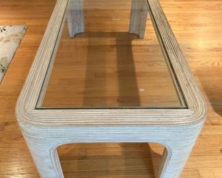 Rectangular glass top coffee table with a curved textured rattan style frame