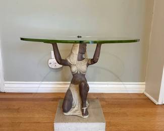 Egyptian inspired sculptural figure table supporting a round glass top on raised arms