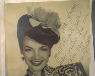 Vintage Hollywood portrait with a handwritten dedication beside a woman in a feathered hat