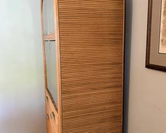 Side view of the rattan display cabinet showing its curved profile and layered construction