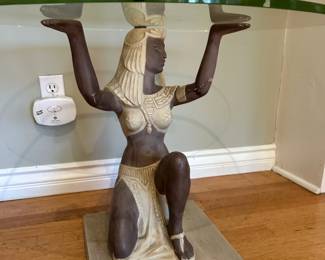 Closer view of the Egyptian figure table showing its contrasting finish round glass top and rectangular base