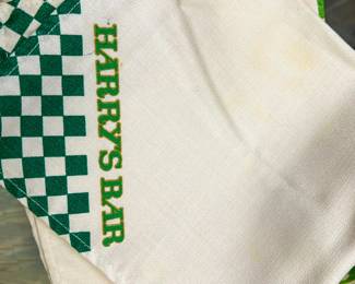 White woven textile with green checkerboard border and Harrys Bar lettering