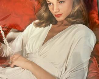 Color Hollywood portrait of a reclining brunette performer in a white blouse against a red cushion