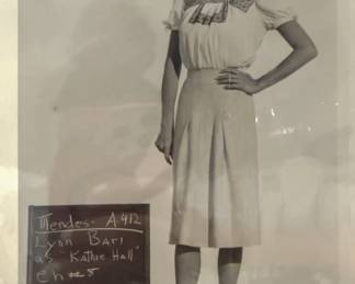 Black and white costume test photograph of a short sleeved dress with a production slate visible