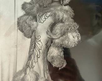 Full length black and white portrait of an elaborate feathered stage costume and wide brimmed hat