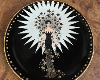 Black decorative plate with a glamorous fashion figure beneath a white starburst motif