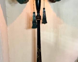 Black Floor Lamp with Green Tasseled Shade A tall floor lamp with a black turned column and painted gold detailing, fitted with a shade trimmed in heavy green tassels. The shade is dark with a silky finish and the tassel trim is full on all sides. Working condition not confirmed — the lamp was not tested. Sold as found.