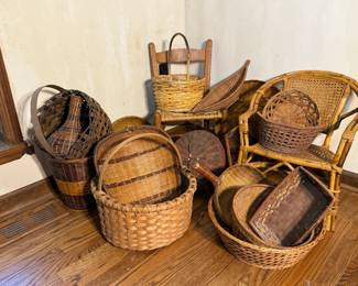 Large Woven Basket Lot A large grouping of woven baskets in assorted sizes and weaves, including tall floor baskets, round gathering baskets with arched handles, a wicker armchair, a rectangular tray basket, a wall-mount basket on a wooden hanger, and several nesting rounds. The weaves range from tight splint to open reed in natural and darker stained tones. A versatile lot for display, storage, or resale.