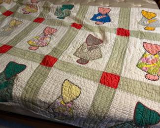 Appliqué Quilt with Green Sashing - A hand-appliquéd quilt with bonneted figures worked in assorted print fabrics, set in a grid of green sashing with red corner squares on a cream ground. The hand quilting is even throughout and the appliqué stitching is tight across every block. The prints carry a wide range of colors — teal, yellow, rose, lavender, and brown — against the pale ground. A well-made handmade quilt with strong visual appeal.