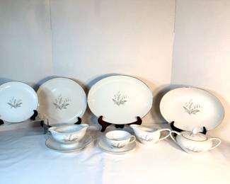 China Service with Silver Wheat Pattern A china service in white featuring a silver wheat sheaf motif and platinum rim banding. The set includes oval serving platters in multiple sizes, dinner plates, saucers, teacups, a creamer, and a covered sugar bowl. The wheat design is finely drawn and the platinum edges are bright throughout. A refined mid-century formal pattern.