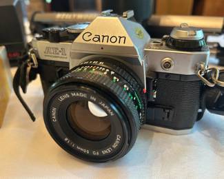 Canon AE-1 Program 35mm SLR with 50mm Lens A Canon AE-1 Program 35mm film camera in the classic chrome-and-black body, fitted with a Canon FD 50mm f/1.8 lens marked "Lens Made in Japan." The body and lens present clean with the badging bright and legible, and a neck strap is attached. Working condition not confirmed — shutter, meter, and light seals were not tested, sold as found. The AE-1 Program remains one of the most sought-after vintage 35mm SLRs among film photographers, and the fast 50mm prime is a desirable pairing.