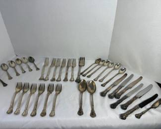 Sterling Silver Flatware Set A sterling silver flatware set in an ornate pattern with scrolled and beaded handle detail. The set includes dinner forks, salad forks, teaspoons, soup spoons, serving spoons, and knives with matching sterling handles. The pieces show a bright polished surface with the pattern well defined throughout. Sterling flatware holds its value on both the pattern and the silver itself.
