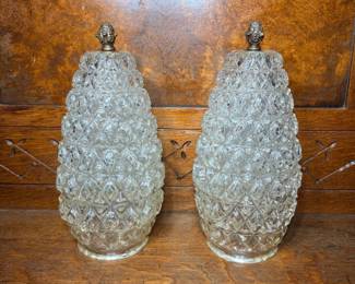 Pair of Pressed Glass Pineapple Lamp Globes with Brass Finials - Two matching pressed glass globes in a deep hobnail pineapple pattern, each fitted with an ornate cast brass finial cap. The glass is clear and bright with strong pattern definition and no visible chips or cracks in the photos. The brass finials show a warm patina consistent with age. These would suit a buyer restoring a vintage lamp or hurricane fixture, or anyone after a decorative matched pair.