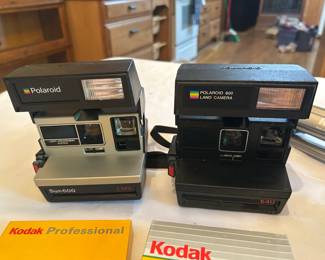 Polaroid Instant Camera Pair with Kodak Materials Two vintage Polaroid instant cameras: a Polaroid Sun 600 LMS in silver and black, and a Polaroid 600 Land Camera 640 in black with the rainbow stripe logo. Both show light surface wear consistent with age and storage. A Kodak Professional folder and a Kodak print folder are included. Working condition not confirmed — neither camera was tested and no film was loaded, sold as found. Polaroid 600-series cameras have a devoted following now that compatible film is produced again.