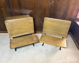 Pair of Antique Cast Iron School Desks - Two matching antique school desks with folding wooden seats and ornate cast iron frames, sold as a pair. Both have been refinished in a warm gold-toned paint over the wood, with the cast iron bases finished in black. The surfaces show light scuffs and brush marks consistent with a previous refinish, and the folding mechanisms appear intact. Antique schoolhouse desks are a steady seller for farmhouse and industrial decor, and finding a matched pair is uncommon.