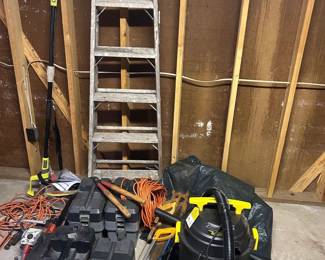 Ladder, Tool, and Shop Equipment Lot A garage lot including an aluminum step ladder, a wet/dry shop vacuum with hose, multiple hard-sided power tool cases, orange extension cords, a pole saw, and two sledgehammers or mauls. Also present is what appears to be a large black equipment bag. Contents of the closed tool cases were not verified, and no power equipment was tested — working condition not confirmed, sold as found. A good working lot for a contractor, homeowner, or picker
