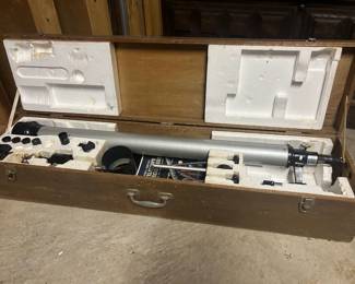 Telescope with Wooden Storage Case and Accessories A refractor telescope with a white tube, finder scope, and tripod mount, packed in fitted foam inside a wooden carrying case with additional eyepieces and accessories in the lid compartment. The optics and mount appear complete as packed. The brand and model markings are not legible in the photo and should be confirmed from the tube. Working condition not confirmed — optics were not tested, sold as found. This connects directly to the astronomy book library and celestial globes elsewhere in this sale.