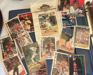 Large Sports Card Collection with Storage Boxes and Binders A large sports card collection including four full storage boxes of cards, a stack of binders and sheets, loose cards in top loaders, and two framed baseball collector plates. The collection covers multiple brands and years across baseball and basketball. Individual cards have not been graded or itemized. Volume like this is where buyers hunt for what got missed.