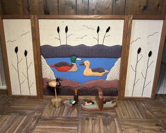 Duck Wall Art Panels with Carved Duck Decoys A three-panel framed wall grouping showing a mallard scene worked in fabric, with cattails on the two side panels, all set in wood frames. Included are two carved wooden ducks mounted on wood bases and a taller standing duck figure. The panels are clean and the frames are intact. A coordinated set for a lodge, den, or hunting-themed room.