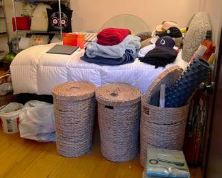 Wicker hampers, a twin bed and frame, and bedding are shown in this photo.
