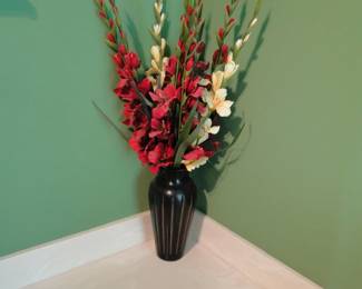 Faux florals in black ridged vase on the side of the bathtub