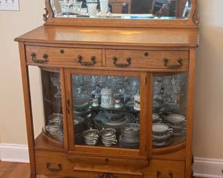 Oak curio server with beveled mirror on top and curved glass on sides