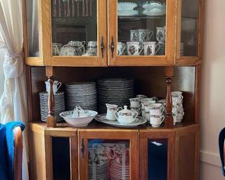 Corner china cabinet with glass-paneled upper and lower doors.