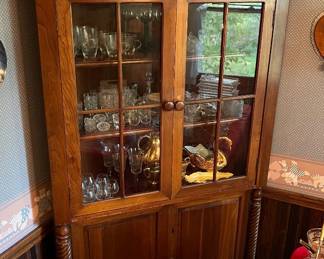 Corner china cabinet with glass-paneled upper and lower doors.