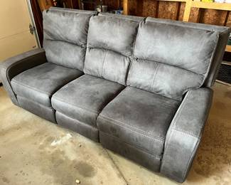 Gray faux-leather reclining sofa with white contrast stitching.