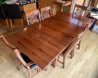 Mission-style rectangular wooden dining table paired with matching slat-back chairs.
