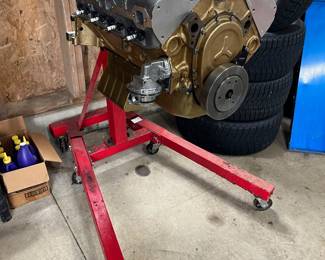 V8 small-block engine on an engine stand, featuring finned Edelbrock aluminum valve covers and a gold-painted oil pan.
