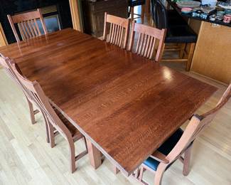Mission-style rectangular wooden dining table paired with matching slat-back chairs.