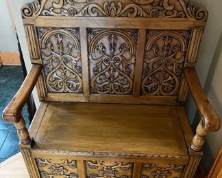 Wooden storage bench with an ornate floral and scroll backrest.