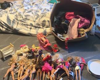 Box of Barbie like dresses and dozens of dolls