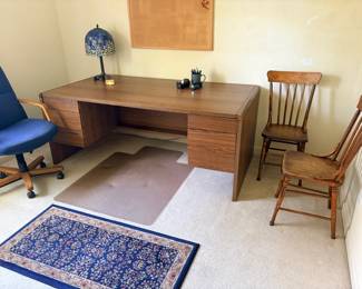 Large office desk with two wooden chairs and office chair, One of several area rugs and chair mat. 