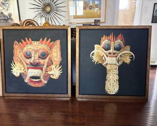 Pair of Asian-Inspired Framed Artworks  Striking coordinating pair of framed decorative artworks featuring intricately detailed ceremonial mask and dragon imagery in rich shades of red, gold and cream against dramatic black backgrounds. Matching warm metallic-toned frames complete the look.  Bold and highly decorative, the pair makes a beautiful statement displayed side by side and works especially well in an eclectic, global-inspired or contemporary interior.  Sold as a pair.