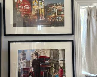 Pair of Framed London Photographic Prints  A coordinating pair of framed London photographic prints featuring iconic city scenes with classic red double-decker buses. One captures the vibrant vintage advertising of Piccadilly Circus, while the other depicts a traditional London street scene with a uniformed police officer and red buses.  Beautifully presented in matching black frames with wide white matting, the pair adds a sophisticated British touch to a gallery wall, office or living space.  Sold together as a pair.