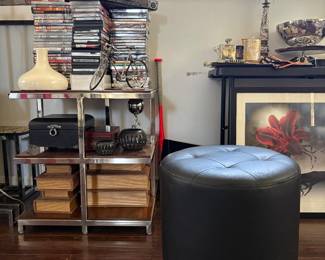 Williams Sonoma Side Table, Ottoman & Decorative Storage  Shown here is one of two coordinating Williams Sonoma side tables, featuring a polished metal frame with warm wood shelving. Also shown are a round black upholstered ottoman, decorative book-style storage boxes and additional home accessories.  The wood on the Williams Sonoma tables shows some light sun fading and slight variation in color, but otherwise presents well.  The two Williams Sonoma side tables are available separately or as a pair. Other items shown are sold individually.