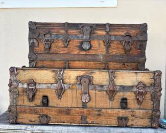 Pair of Antique Wood & Iron Steamer Trunks  A striking pair of antique wooden trunks featuring substantial iron hardware, decorative corner fittings, original-style latches and beautifully aged wood with a rich, timeworn patina.  These character-filled trunks have wonderful architectural detail and authentic signs of age and use, making them beautiful statement pieces for décor, display or storage.  Believed to date from the late 19th to early 20th century. Exact age unknown. Sold together as a pair.  Please message for dimensions, additional photos, condition details or information.