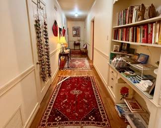 The long hallway towards linens and the primary bedroom is lined with beautiful rugs!