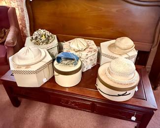 Collection of vintage hats and hat boxes in front of full sized bed