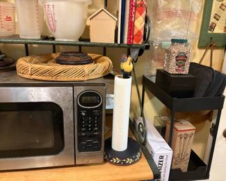 Right side of third shelf has paper towel holder, microwave oven, miscellaneous on top of microwave