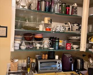 Lots of items in cabinet including glasses, drink containers, dishes, bowls, toaster & toaster oven, silverware sets, S/P sets,