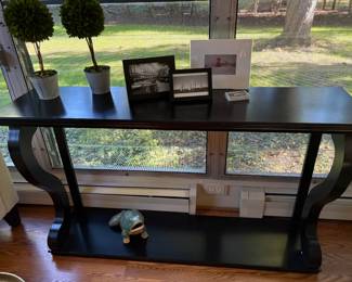 Black tall console table with boxwood decor and framed prints