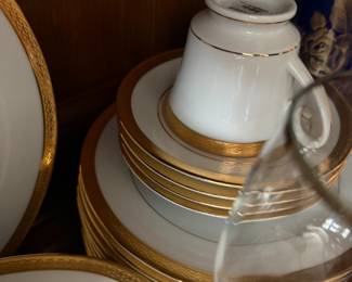 White porcelain cup and gold-rimmed plates and saucers stacked