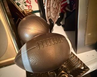 Gold-tone decorative football and basketball sculptures on shelf