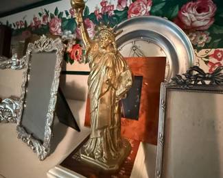 Gold Statue of Liberty figurine with ornate picture frames on shelf