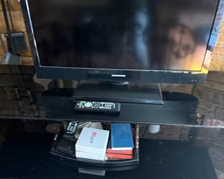 Magnavox flat screen TV with remote on glass stand