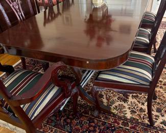 Mahogany dining table with carved pedestal base and striped upholstered chairs